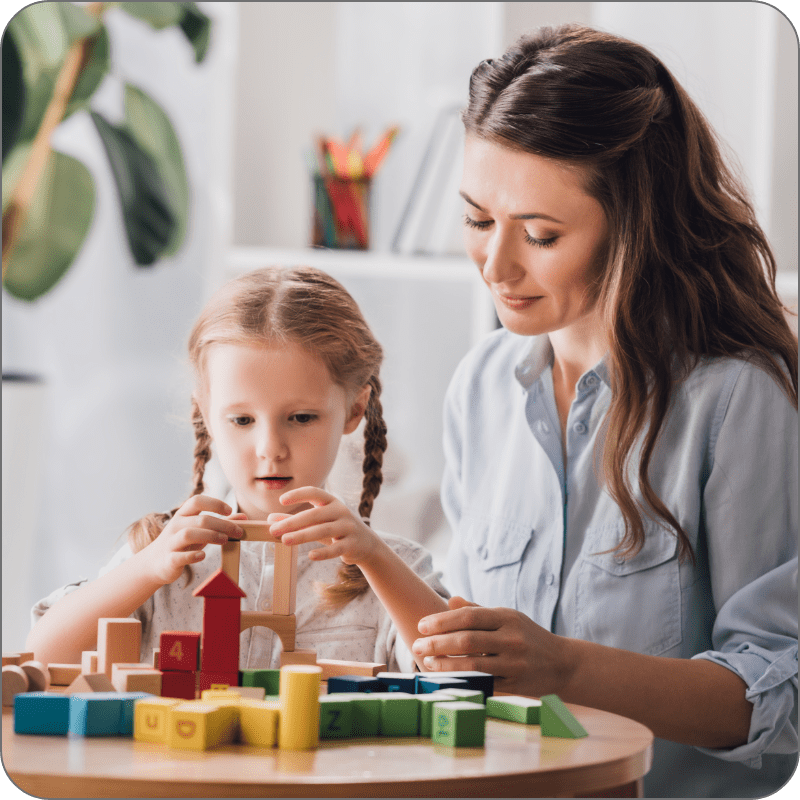 Young child and therapist play with building blocks